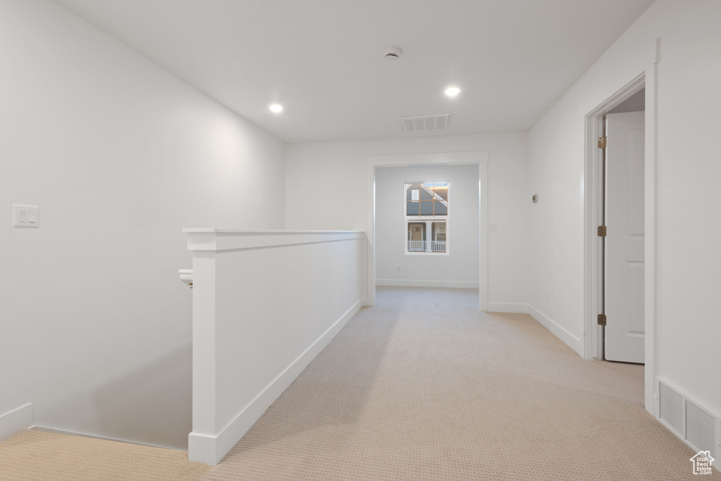 Hallway featuring an upstairs landing, light colored carpet, and recessed lighting