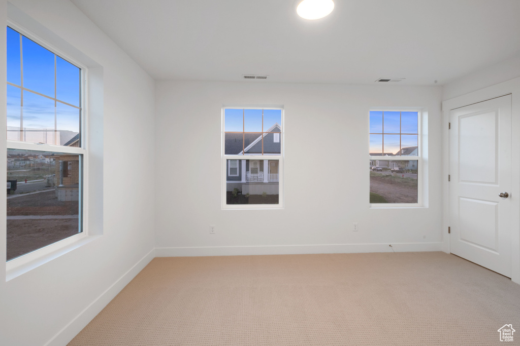 Unfurnished room featuring light carpet and healthy amount of natural light