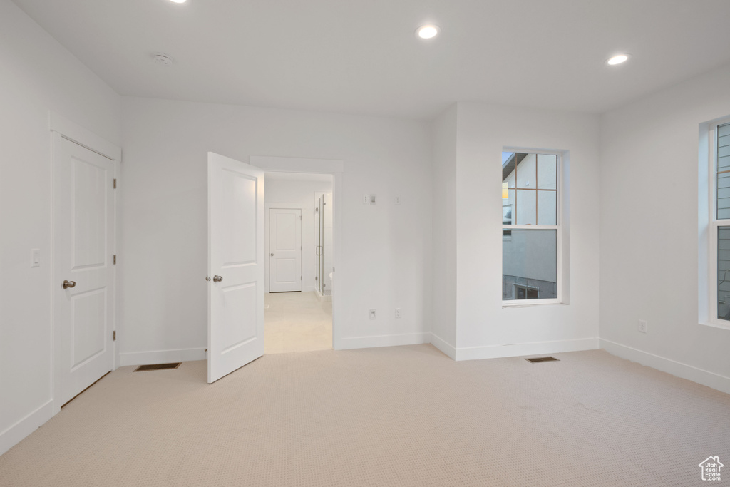 Unfurnished bedroom with light carpet and recessed lighting