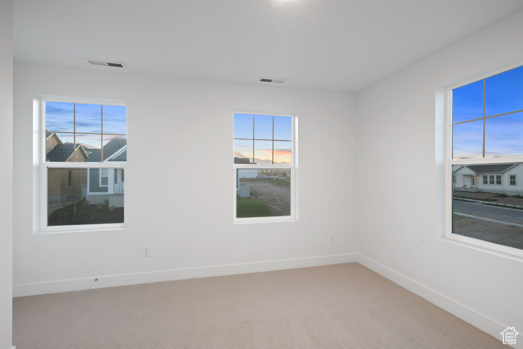 Spare room with baseboards and light carpet