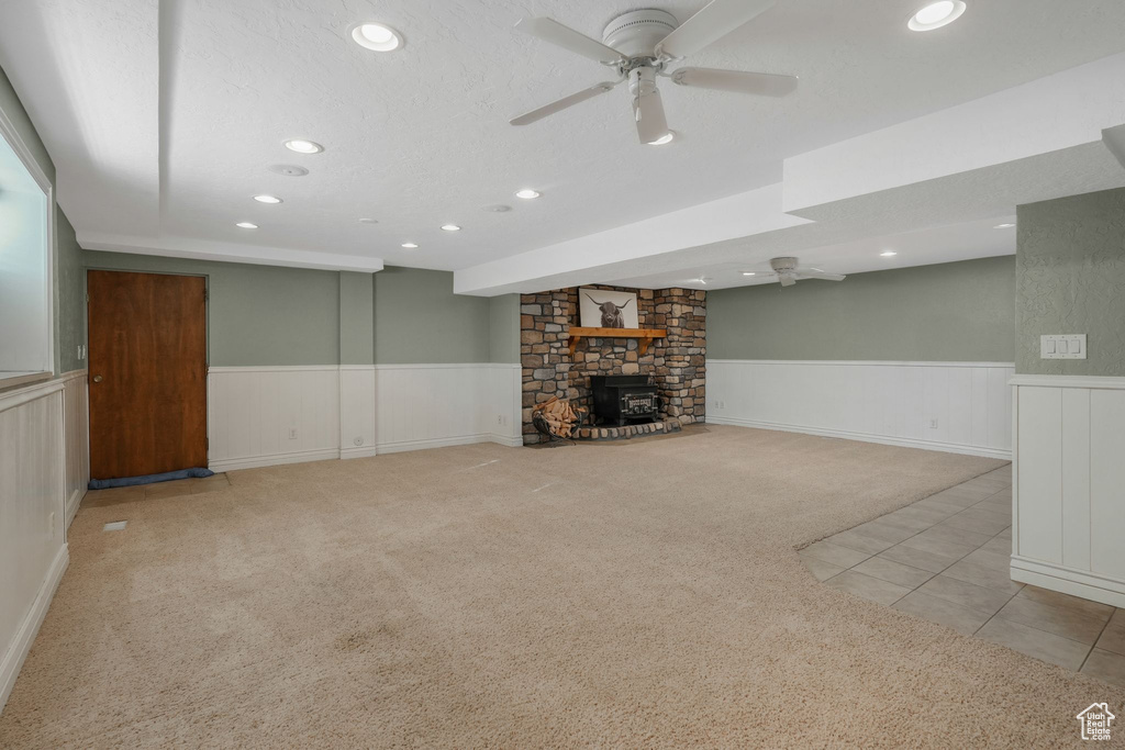 Unfurnished living room featuring ceiling fan, light carpet, and a fireplace