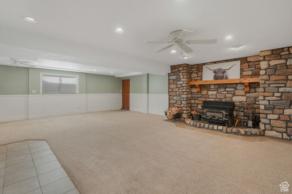 Basement with ceiling fan, light colored carpet, and a stone fireplace