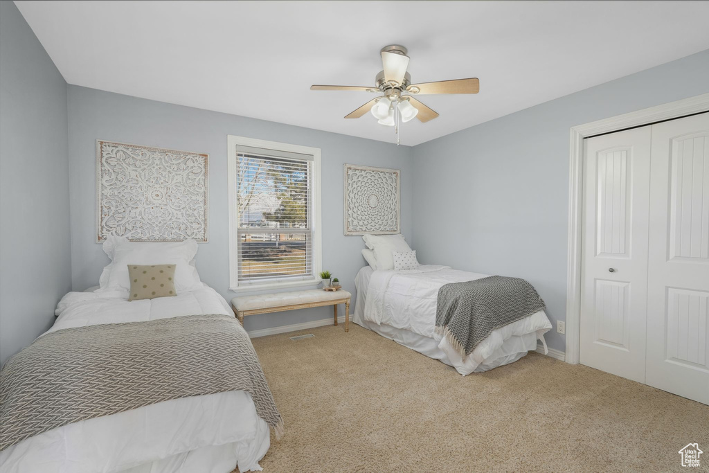 Carpeted bedroom featuring ceiling fan and a closet