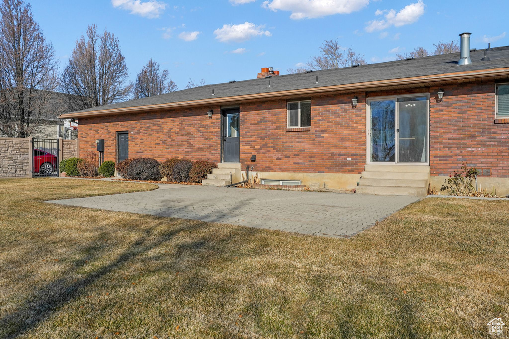 Rear view of house with a lawn and a patio