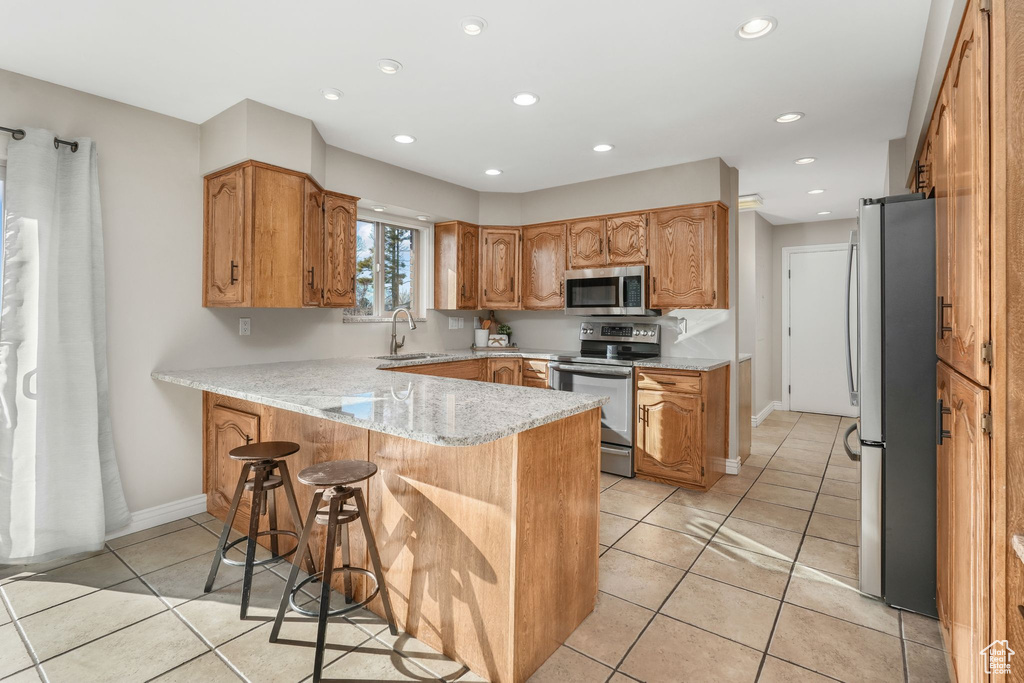 Kitchen featuring stainless steel appliances, sink, a kitchen breakfast bar, kitchen peninsula, and light tile patterned floors