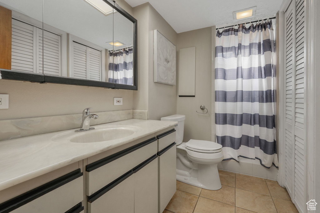Bathroom with toilet, vanity, tile patterned floors, and walk in shower