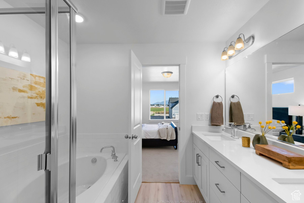 Bathroom featuring hardwood / wood-style floors, vanity, and shower with separate bathtub