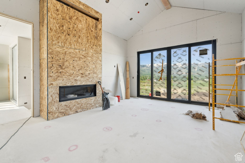 Unfurnished living room with high vaulted ceiling and a glass covered fireplace