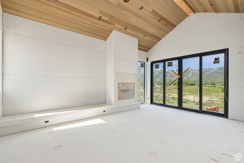 Unfurnished room with wooden ceiling with exposed beams, high vaulted ceiling, and a mountain view