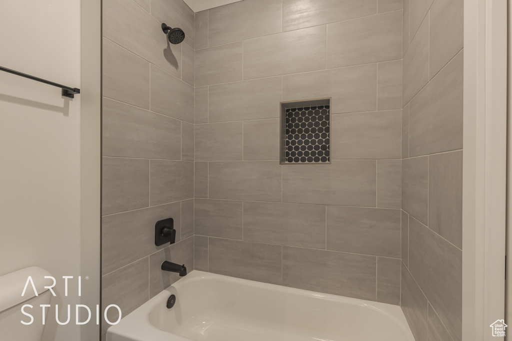 Bathroom with toilet and tiled shower / bath combo
