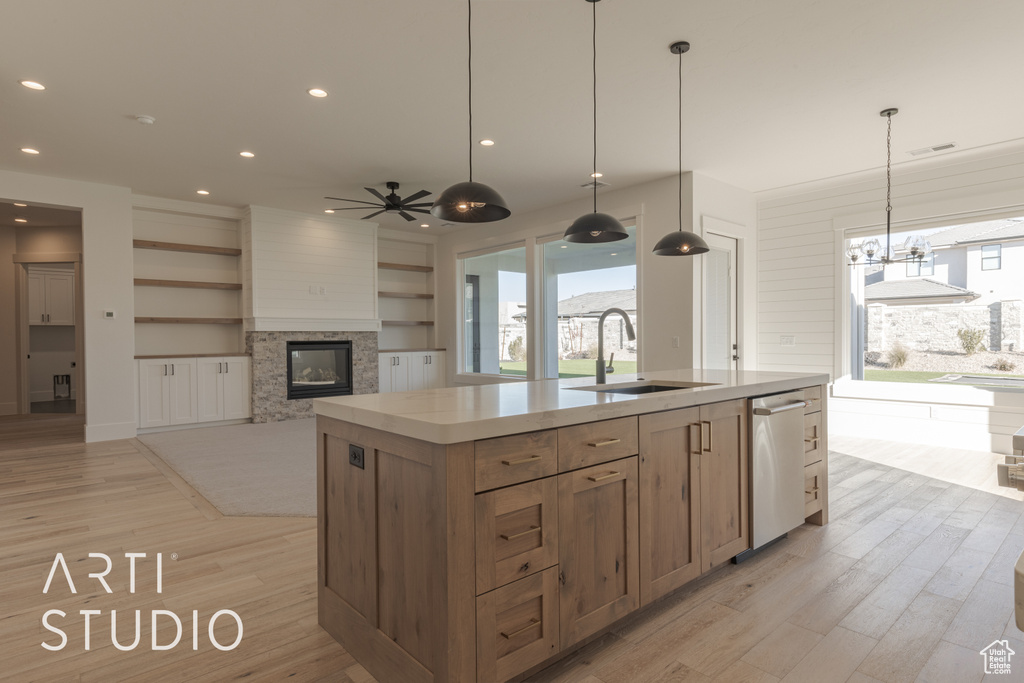 Kitchen with a center island with sink, ceiling fan, a fireplace, dishwasher, and sink