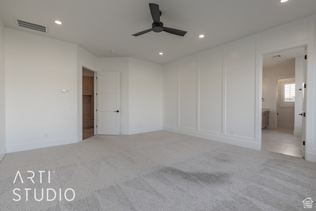 Unfurnished bedroom with ensuite bath, ceiling fan, and light carpet