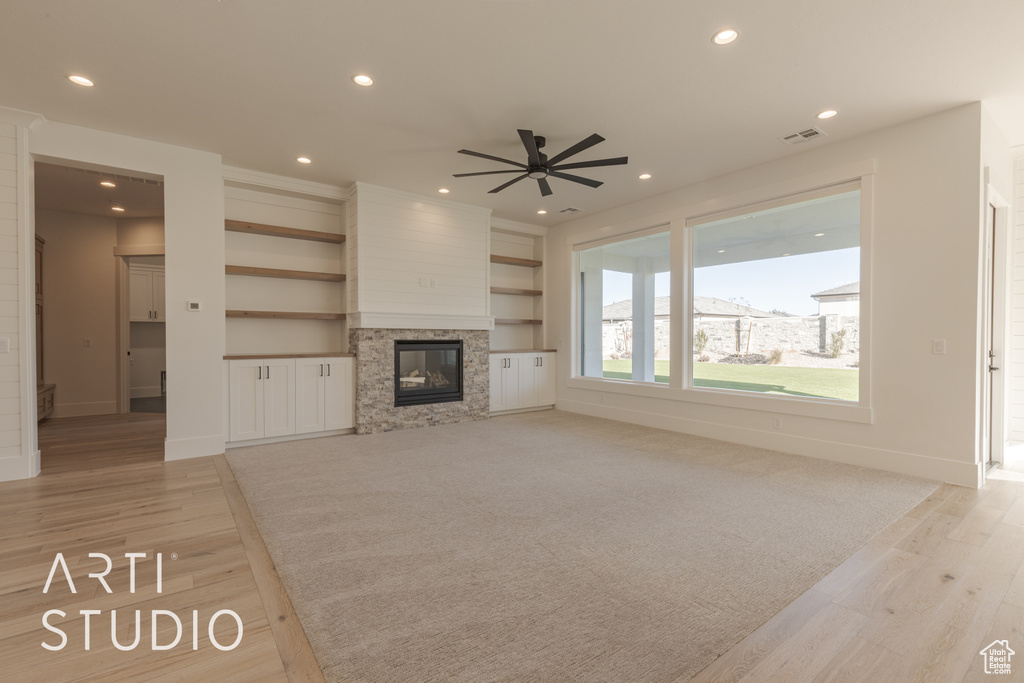 Unfurnished living room featuring ceiling fan, light wood-type flooring, and a fireplace