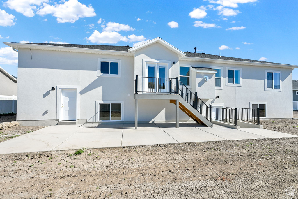Back of house featuring a patio, stucco siding, and stairway