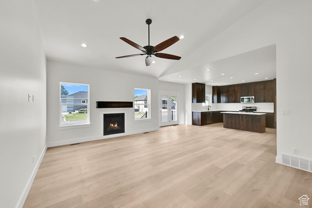 Unfurnished living room featuring ceiling fan, a lit fireplace, visible vents, light wood-style floors, and recessed lighting