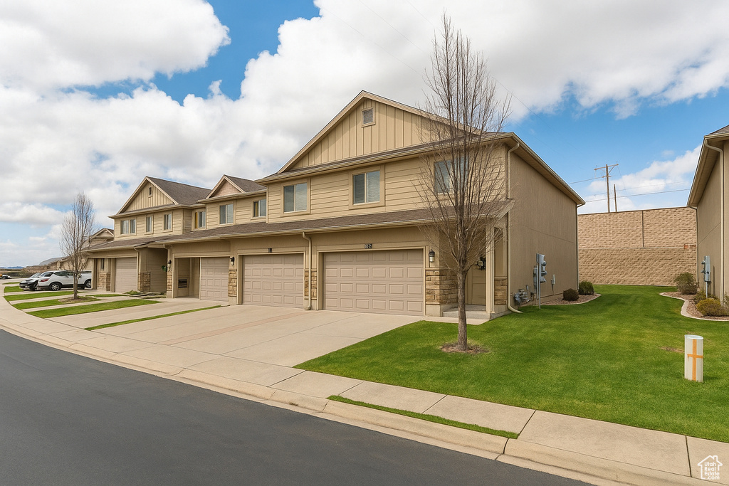 View of front of property featuring board and batten siding, driveway, an attached garage, and a front lawn