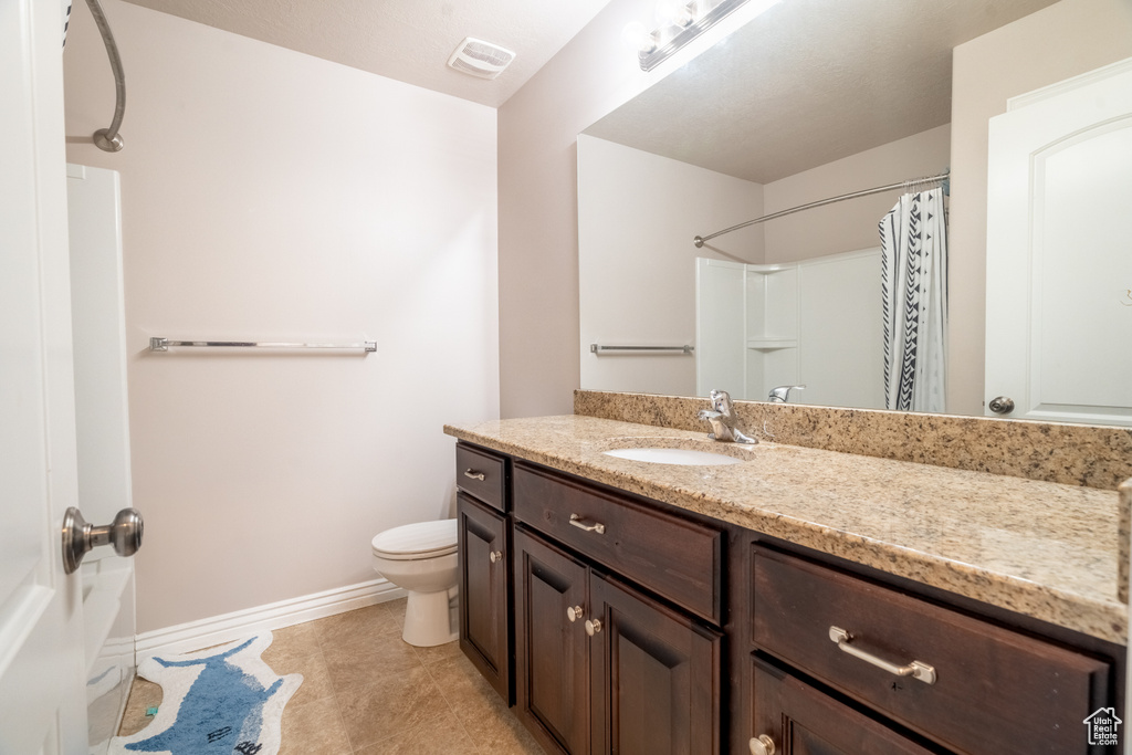 Bathroom with vanity, baseboards, visible vents, tile patterned floors, and toilet