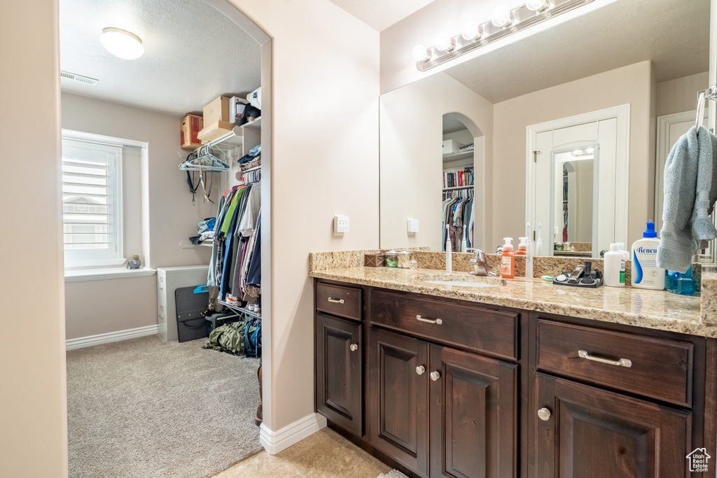 Bathroom featuring visible vents, baseboards, vanity, and a spacious closet