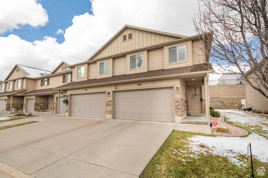 Multi unit property with stone siding, board and batten siding, concrete driveway, and an attached garage