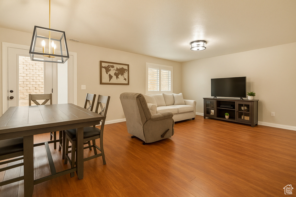 Living room with wood finished floors, a chandelier, and baseboards
