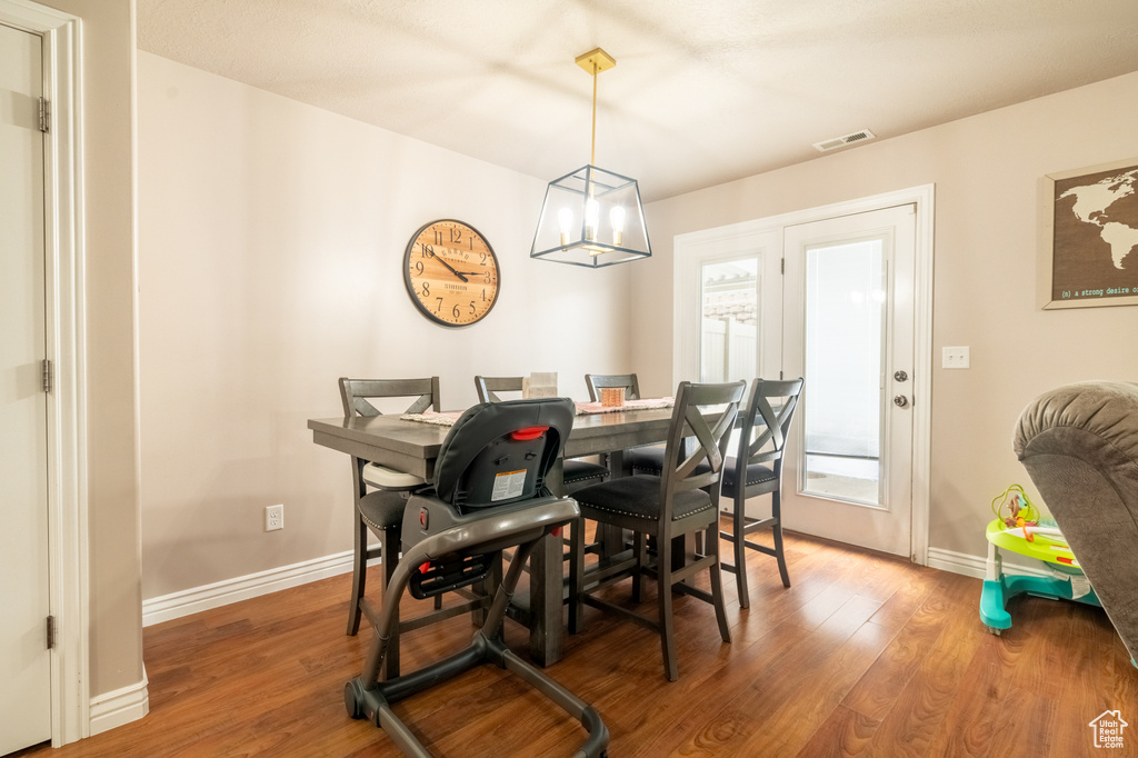 Dining space with visible vents, baseboards, a notable chandelier, and wood finished floors