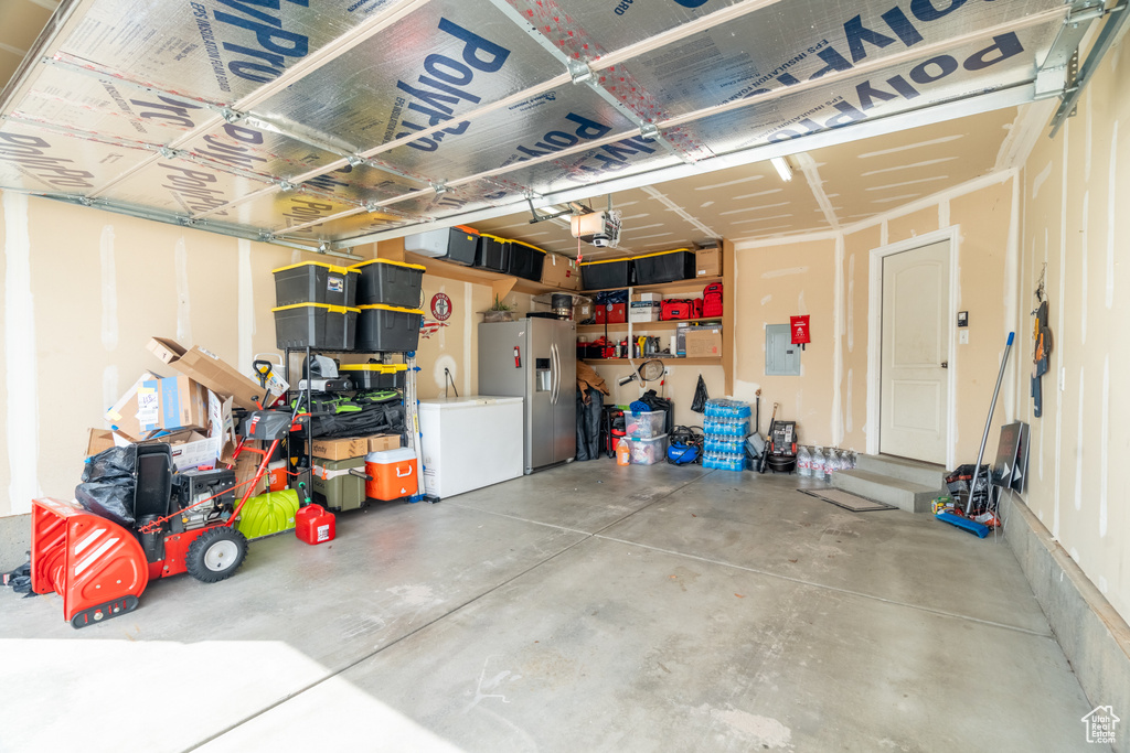Garage with a garage door opener and stainless steel fridge with ice dispenser