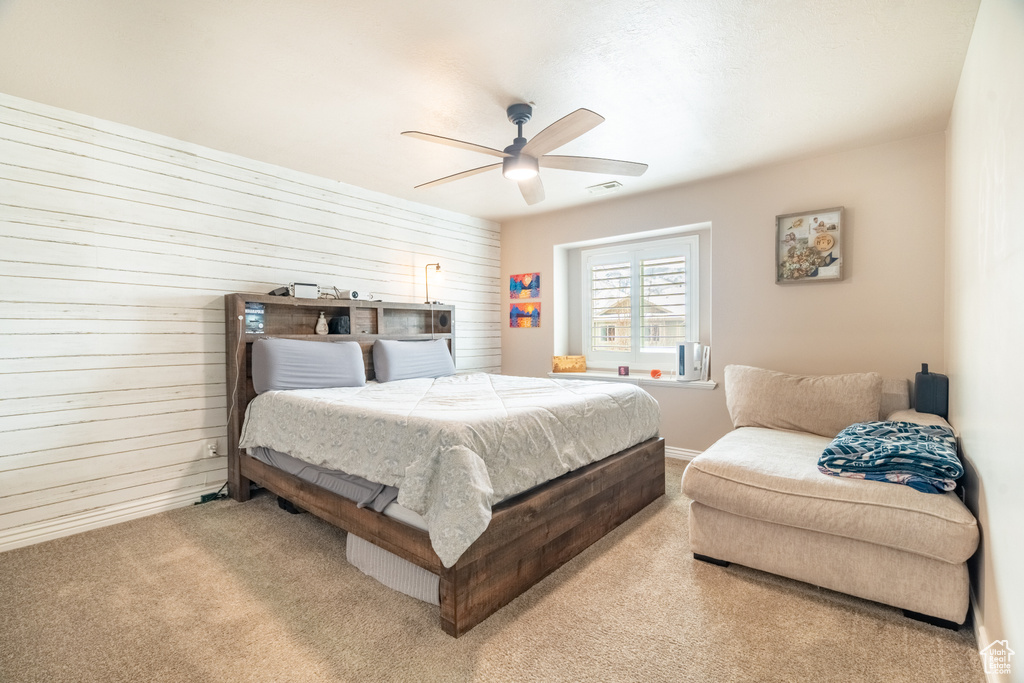 Bedroom featuring wooden walls, visible vents, a ceiling fan, and carpet