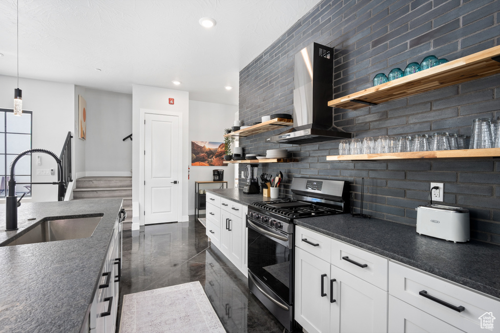 Kitchen featuring tasteful backsplash, sink, white cabinetry, wall chimney exhaust hood, and gas range