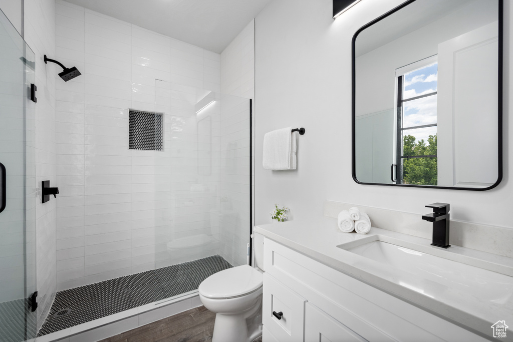 Bathroom featuring hardwood / wood-style floors, toilet, vanity, and an enclosed shower