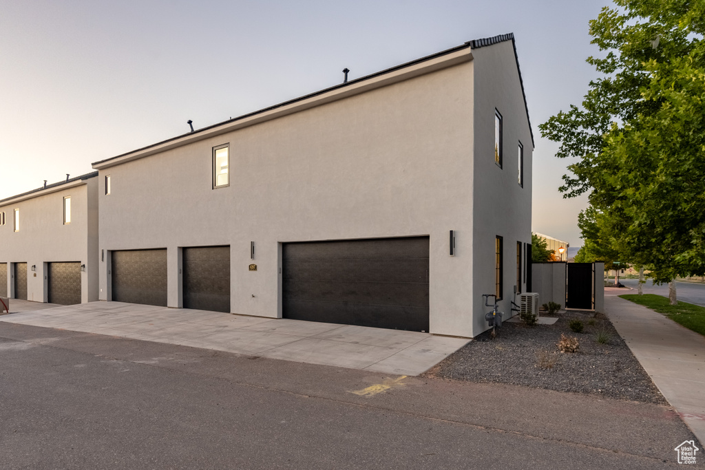 Property exterior at dusk with a garage and central air condition unit