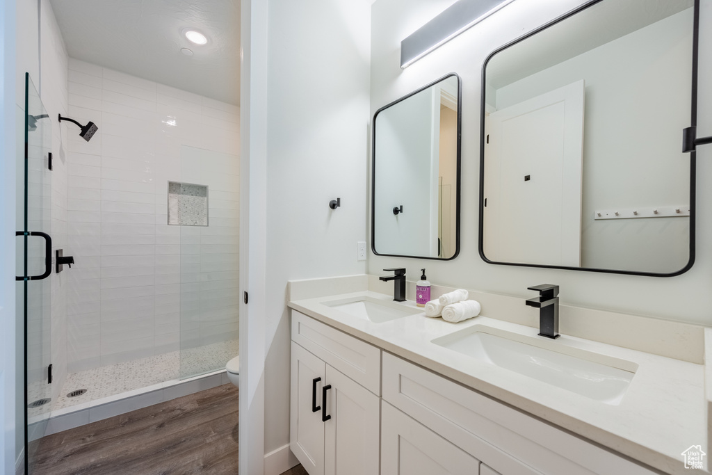 Bathroom with toilet, a shower with door, hardwood / wood-style flooring, and vanity