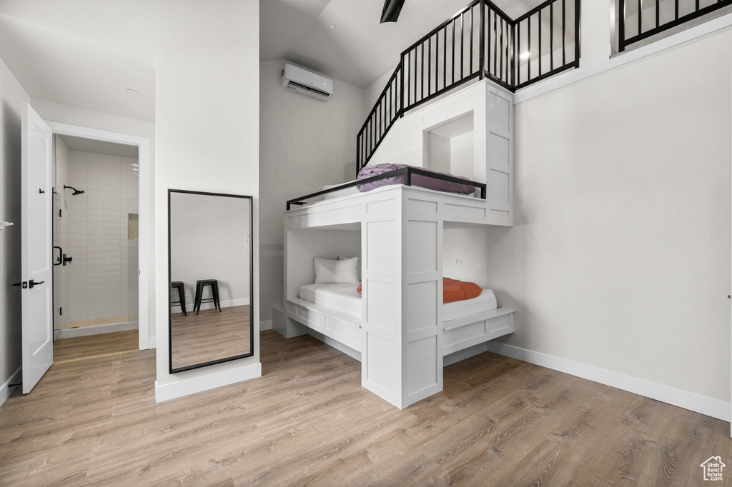 Unfurnished bedroom featuring light wood-type flooring and a wall mounted air conditioner