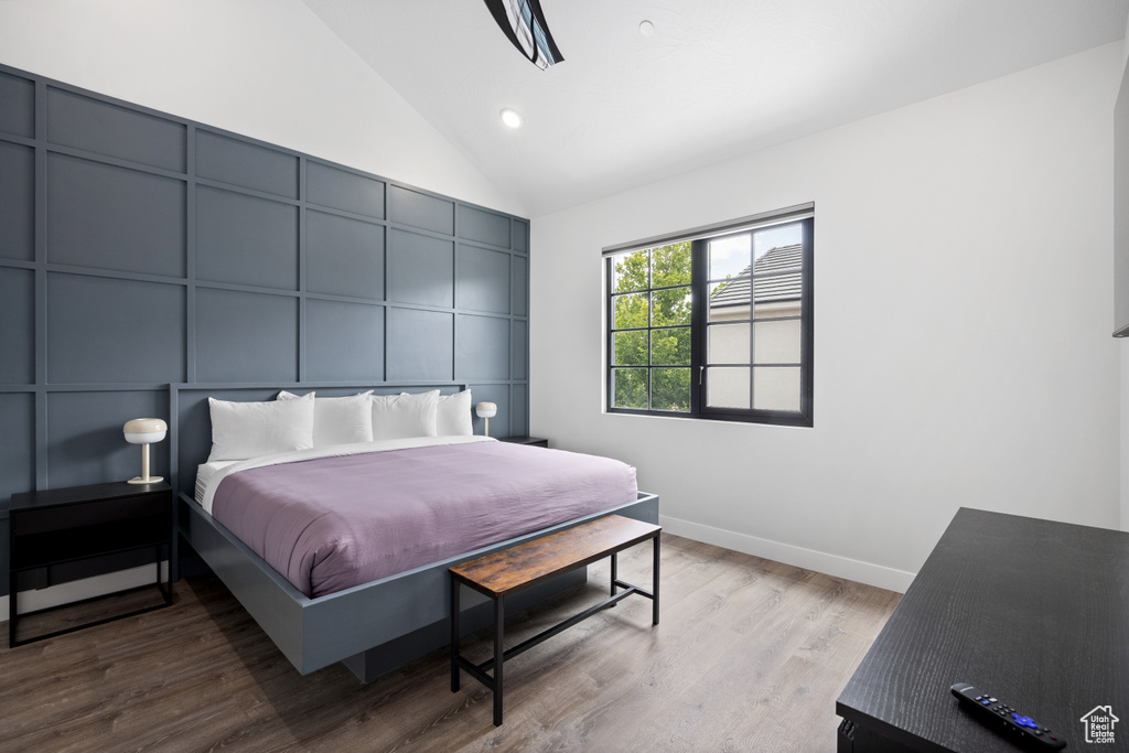 Bedroom with high vaulted ceiling and hardwood / wood-style floors