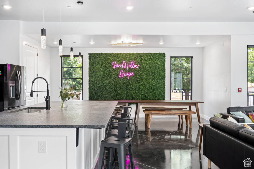 Kitchen with black fridge, plenty of natural light, sink, and pendant lighting