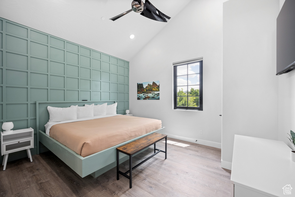 Bedroom featuring ceiling fan, hardwood / wood-style floors, and high vaulted ceiling