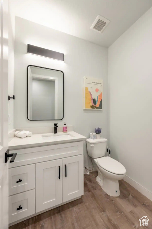 Bathroom featuring toilet, hardwood / wood-style floors, and vanity