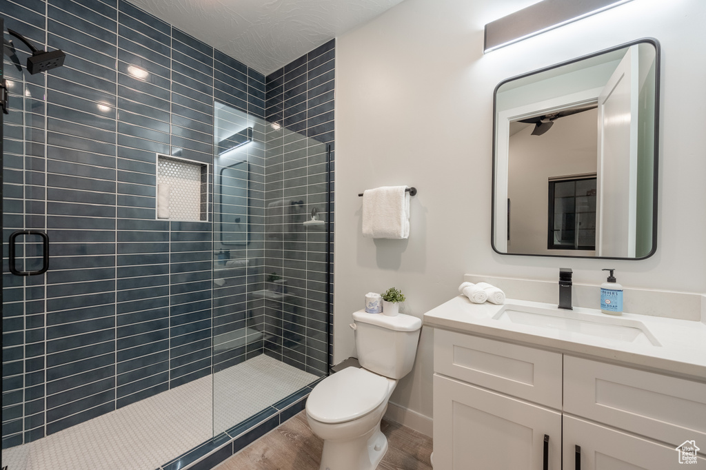 Bathroom featuring wood-type flooring, toilet, walk in shower, and vanity