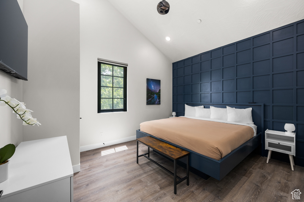 Bedroom with high vaulted ceiling and hardwood / wood-style floors