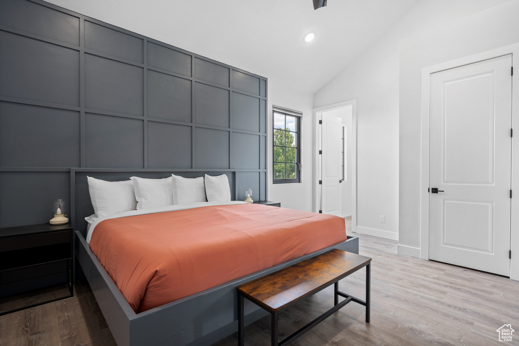 Bedroom with high vaulted ceiling and light wood-type flooring