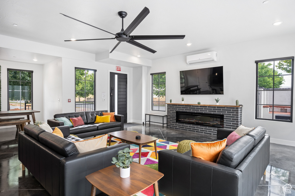 Living room featuring a brick fireplace, a healthy amount of sunlight, an AC wall unit, and ceiling fan