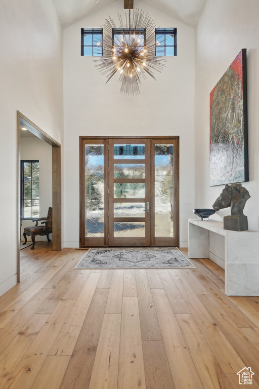 Foyer featuring light wood finished floors, high vaulted ceiling, and a chandelier