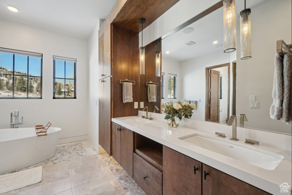 Bathroom featuring double vanity, a soaking tub, recessed lighting, and baseboards