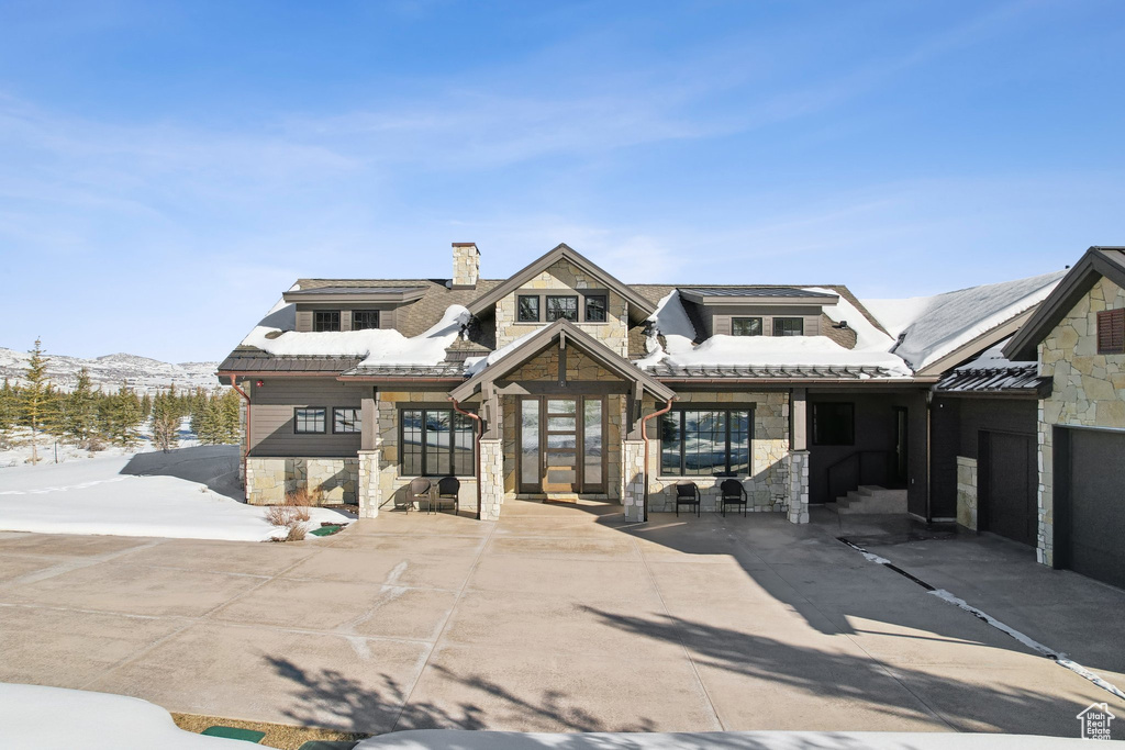 View of front facade with stone siding, a chimney, and a mountain view