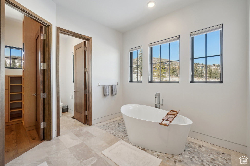 Bathroom featuring a soaking tub, toilet, recessed lighting, and baseboards