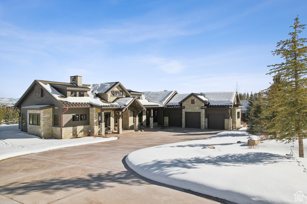 View of front of home with stone siding and a chimney