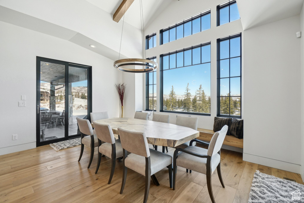 Dining space with plenty of natural light, light wood finished floors, high vaulted ceiling, beamed ceiling, and recessed lighting