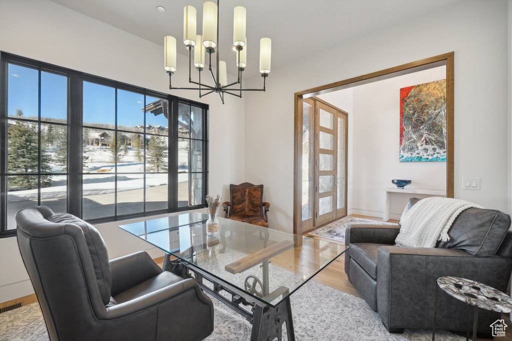 Office with a chandelier, healthy amount of natural light, wood finished floors, and french doors