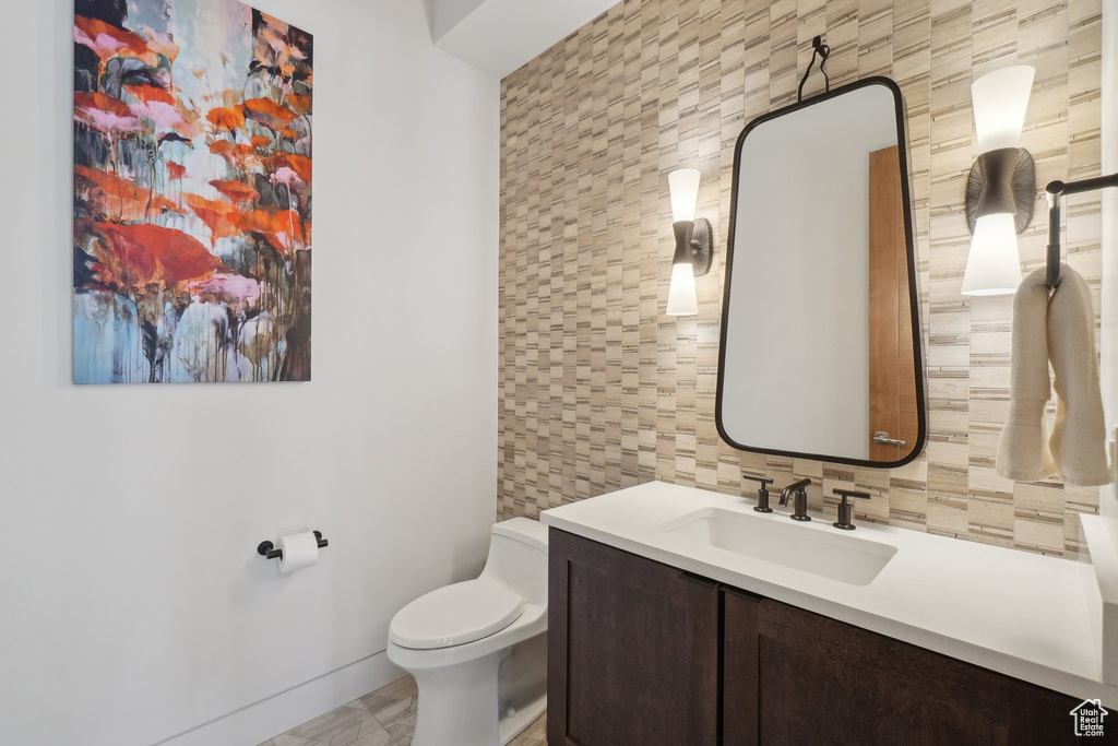 Bathroom featuring vanity, toilet, and decorative backsplash