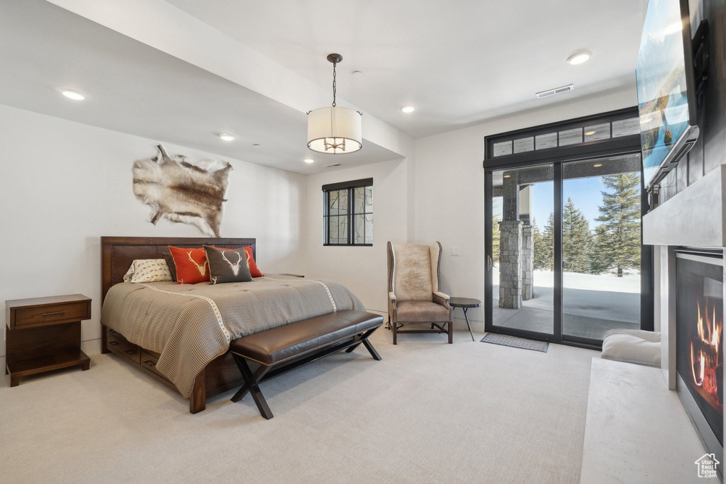 Carpeted bedroom with access to exterior, recessed lighting, and a warm lit fireplace