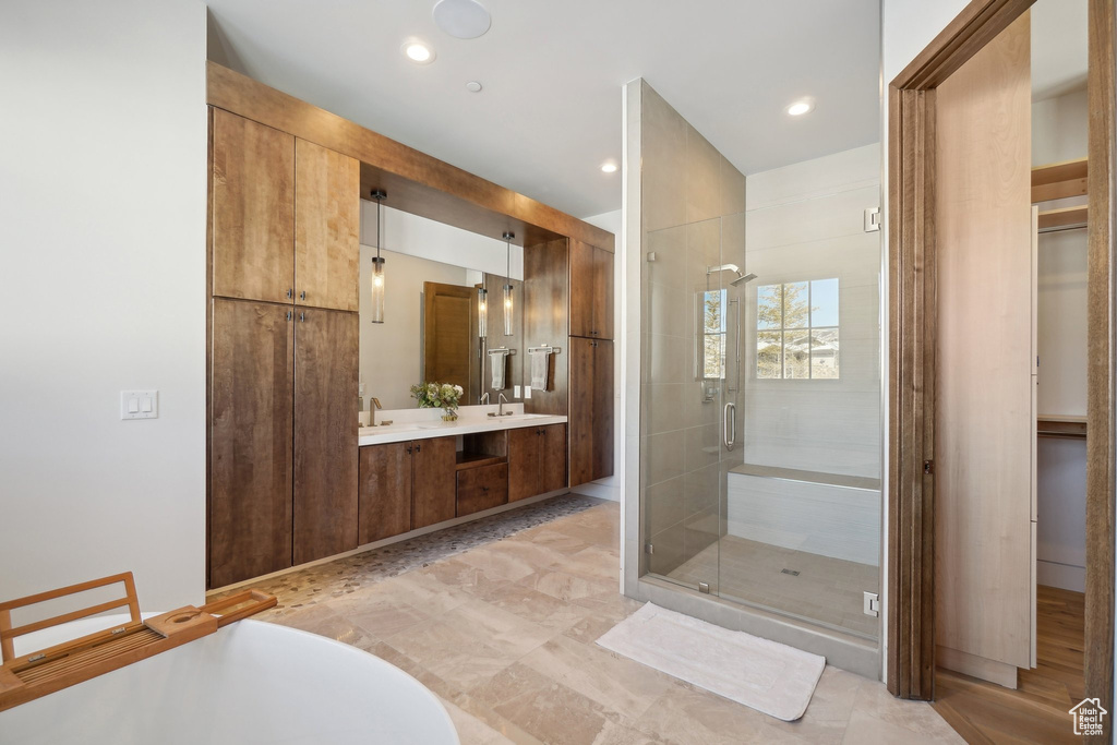 Bathroom featuring a stall shower, double vanity, and a freestanding tub